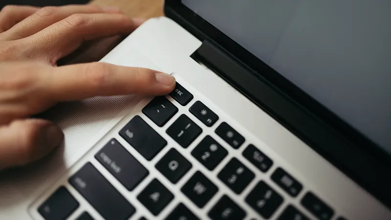 Hands typing on a backlit laptop keyboard in low light