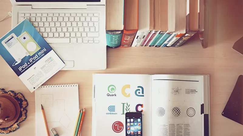 Overhead view of a desk with laptop, books and phone