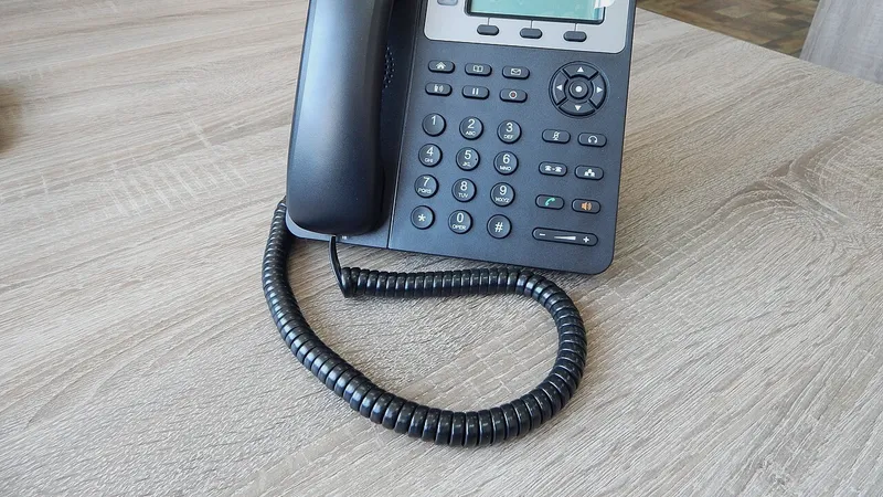 Desk phone with handset on a wooden office desk