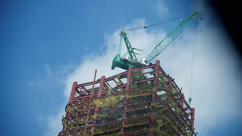 Crane lifting a steel frame section against a blue sky
