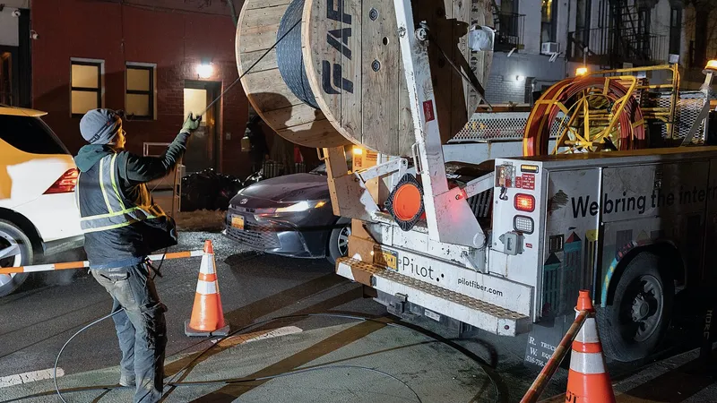 Technician pulling fiber cable from a reel truck at night