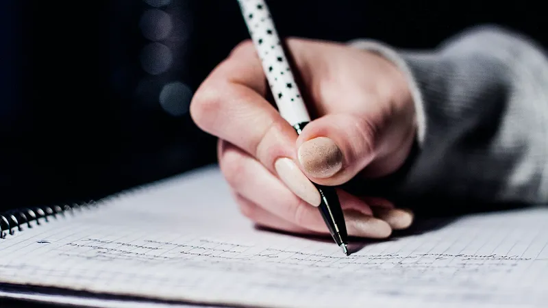 Open notebook, pens and reading glasses on a desk