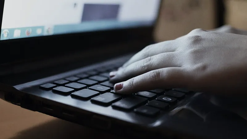 Hand resting on a laptop keyboard in a bright workspace