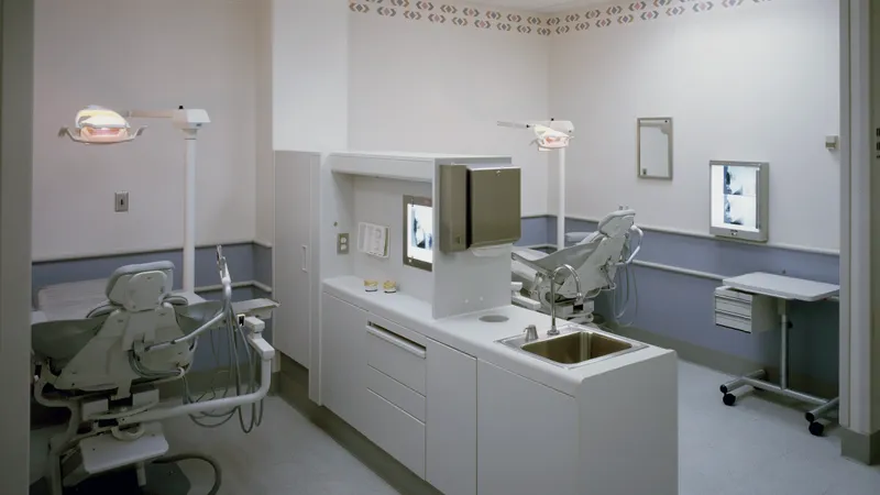 Empty dental operatory with chair, cabinetry and monitor cart
