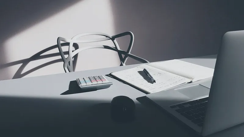 Laptop, calculator and notebook on a white desk