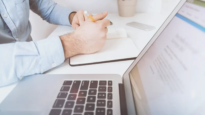 Businessman writing notes beside an open laptop