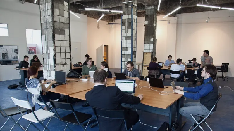 Group of people working on laptops around a shared office table
