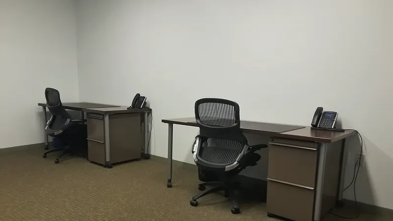 Empty office with two desks, chairs and phones
