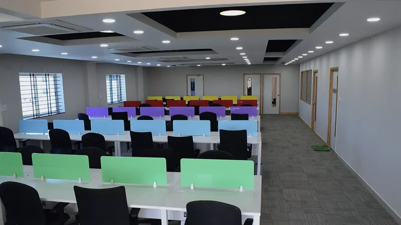 Rows of white desks with coloured dividers in a large open office