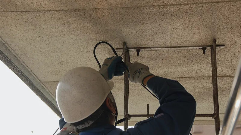 Technician in hard hat fastening cable to a ceiling