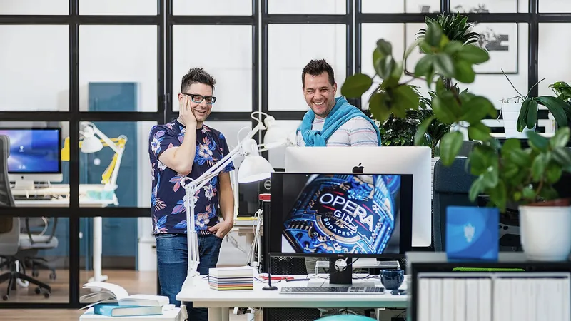 Two designers at a studio desk with a large monitor