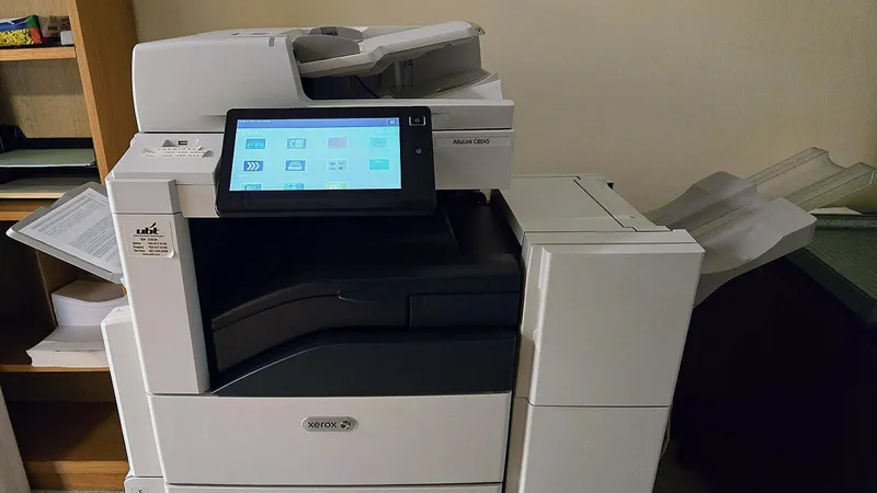 Office multifunction copier and printer beside a paper tray