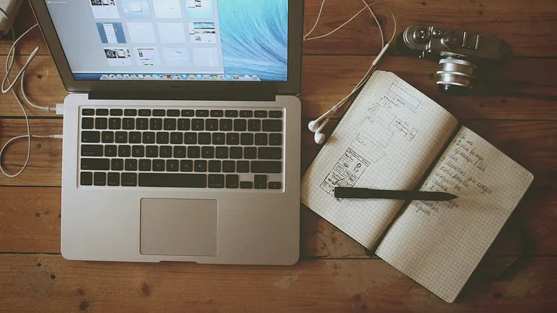 Laptop, notebook and camera on a wooden desk