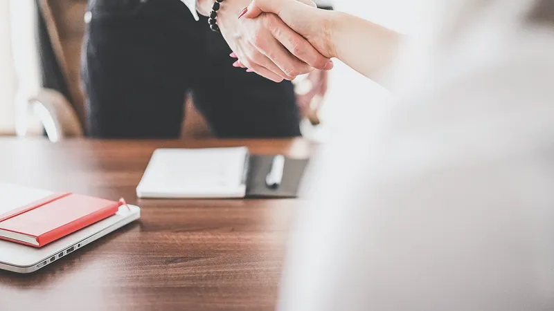 Two people shaking hands across an office desk
