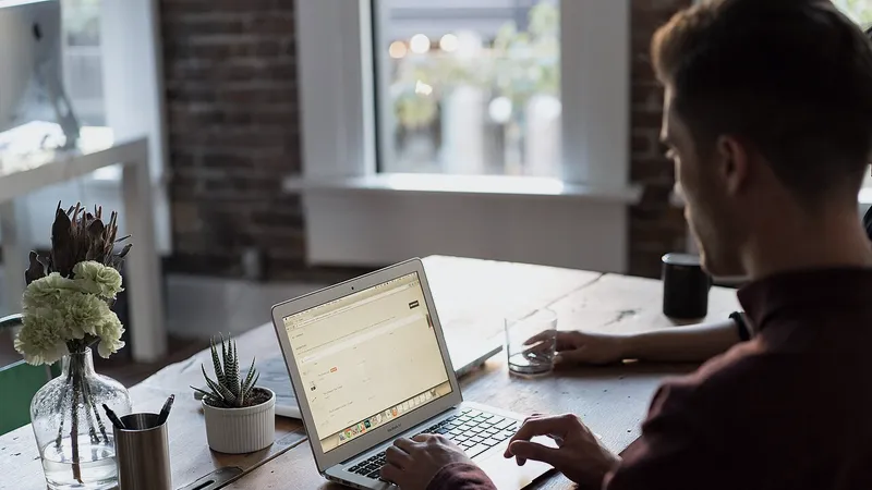 Man working at a laptop by an office window