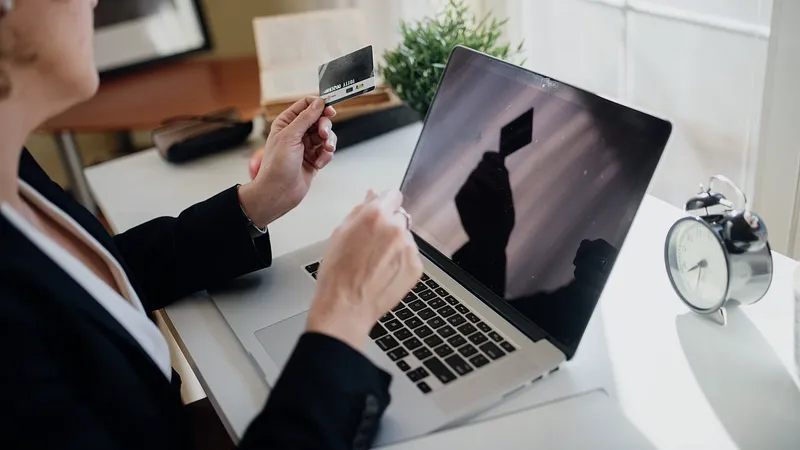 Person at a laptop holding a payment card at a desk