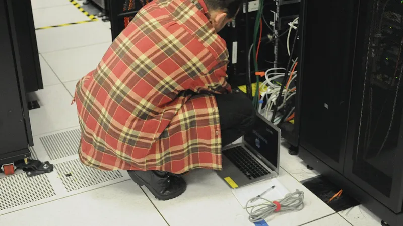 Technician with a laptop kneeling at a server rack