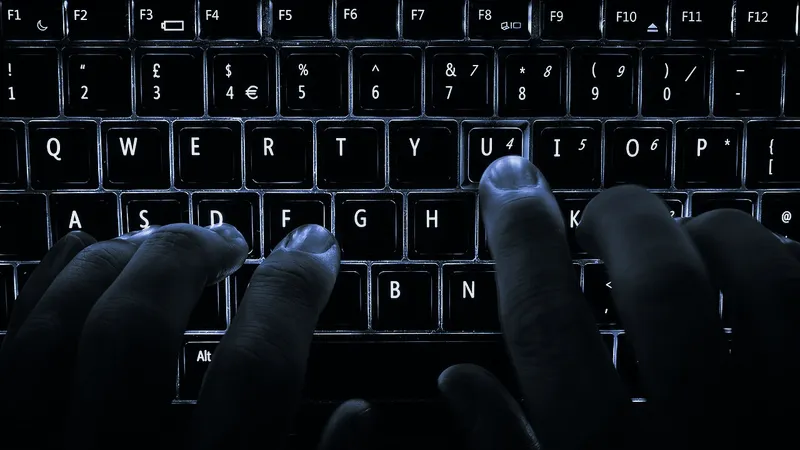Fingers resting on the home keys of a backlit laptop keyboard
