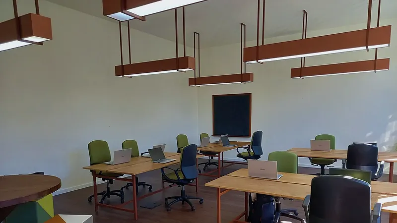 Small office room with wooden desks, laptops and office chairs